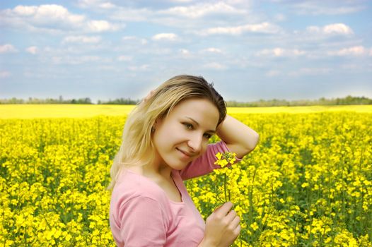 Beautiful girl among blooming rape oilseed field