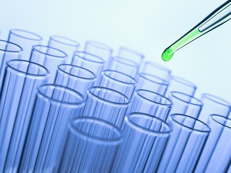 Close up of a pipette dropping a green sample into a test tube.