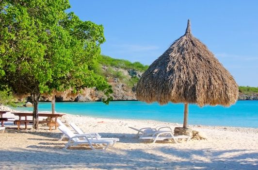tropical beach with chairs and natural made parasol of palm leaves 