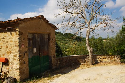 Tuscany country scene with hill on the background, tree and garage on the foreground