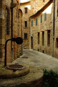 Street of Montepulciano village with a pit in the foreground in Tuscany, Italy