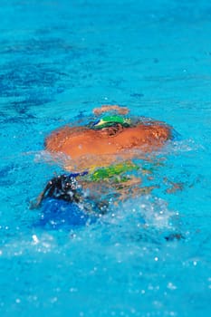 Swimmer under water in the pool, with bright sun