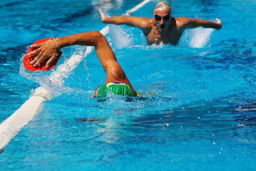 Swimmers training in pool, first one crowling, second one butterfly swimming.