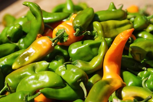 Pile of green chili peppers and some orange ones