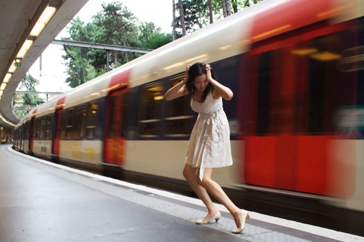 A woman has just missed her train. She's holding her head as the train departs.