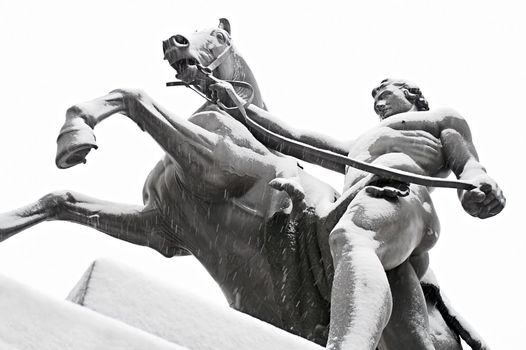 One of the famous "Taming of Horses" public ensemble by Klodt at Anichkov Bridge in St. Petersburg. Russia, while snowing.