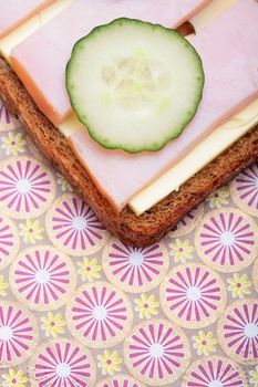 sandwich from pumpernickel bread with butter, ham and cucumber, fragment