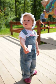 small girl in the blue overalls with ticket in hand