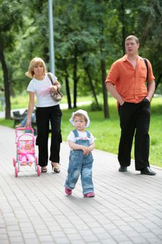 dad, ma and daughter on walk in summer park