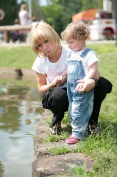 mamma and daughter in park on walk near water