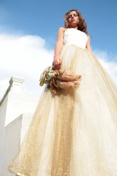 supercilious princess with toy and in white-golden gown on background blue sky