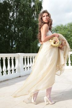 long-haired princess in white-golden gown with loved toy on background banisters