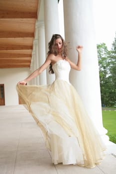 beautiful girl in gown of the bride dances between pillar of the old-time building