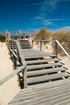 Boardwalk over sand dunes on a sunny day near the beach.