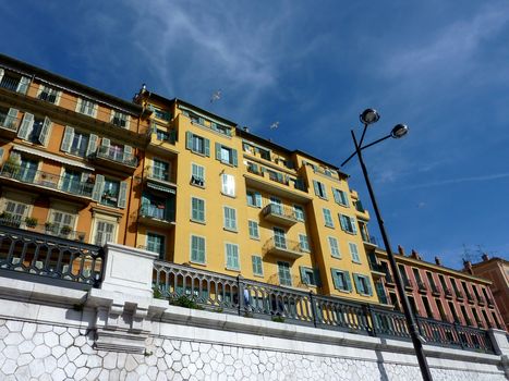 Three birds flying next to beautiful colored buildings in Nice, old port, France