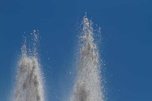 Two plumes of veritical water from a water fountain against a blue sky