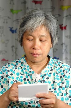 middleage chinese woman playing handheld game console