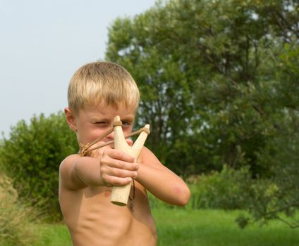 A boy aiming a wooden slingshot.