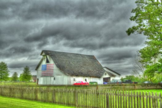 HDR image of a white barn with an american flag on it.