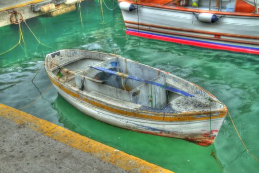 An Italian row boat sitting by the dock.  Shoot in HDR.