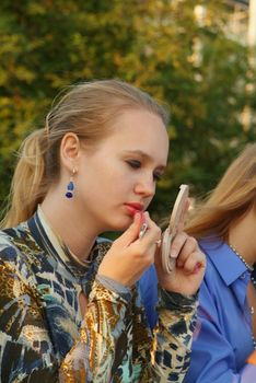 Girls use lipstick outdoor