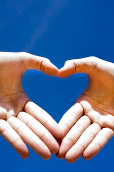 Heart combined from hands on blue background 