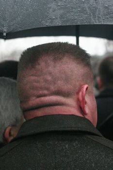 The man with a short hairstyle revolved by a nape to the chamber costs{stands} under a umbrella{parasol} during a rain largly Kharkov Ukraine 19 01 2007