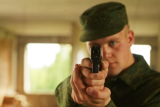 The soldier aims from a pistol.