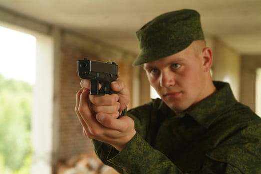 The soldier aims from a pistol.