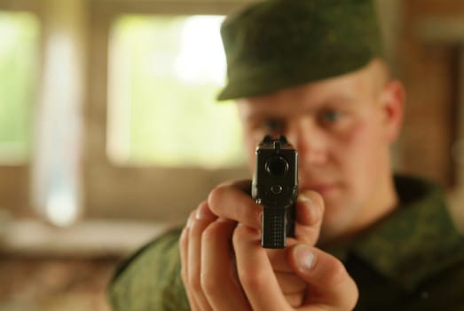 The soldier aims from a pistol.