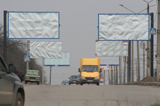Street of city with established empty big boards and a yellow minibus