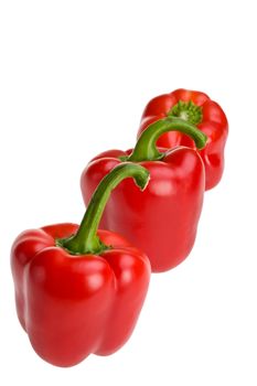 three red bell pepper s in a row isolated on white