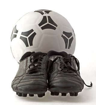 Soccer ball with two old black soccer shoes, isolated over white