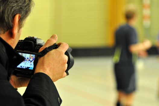 A photographer using his camera to capture a match of floorball.