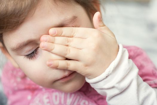 little girl covering her eyes with her hand