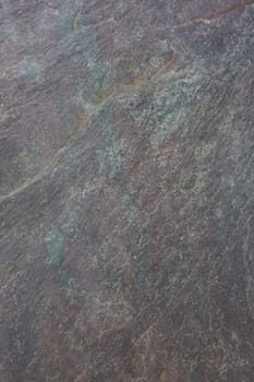 flat, gray, fine-grained, foliated slate rock with purple tint and green spots and veins