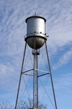 An old metal water tower on a cloudy sky background.