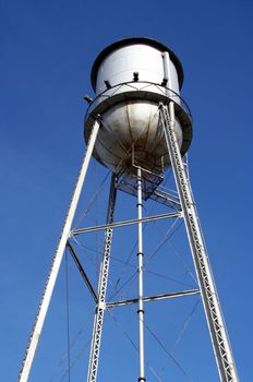 An old metal water tower on a clear blue sky background.