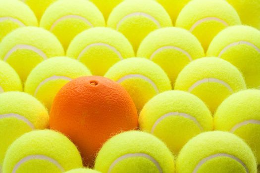 Macro Set of Brand New Tennis Balls and One Orange.