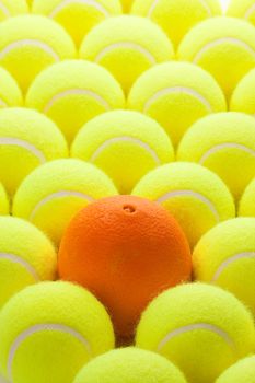 Macro Set of Brand New Tennis Balls and One Orange.