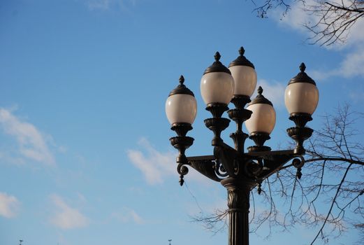 white streetlight on black metal lamppost, blue sky and white clouds