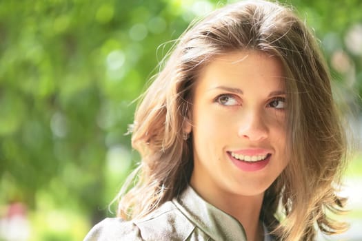 portrait of the beautiful smiling girl with brown hair shining under sunlight