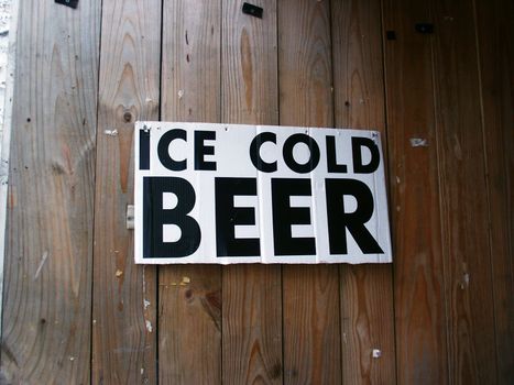 An "Ice Cold Beer" sign hanging on a wooden wall.