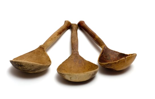 Three ancient wooden spoons on a white background.