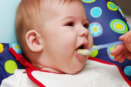 Mother feeding baby food to baby