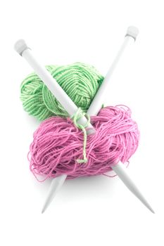 Balls of green and pink  knitting wool or yarn, with silver knitting needles.