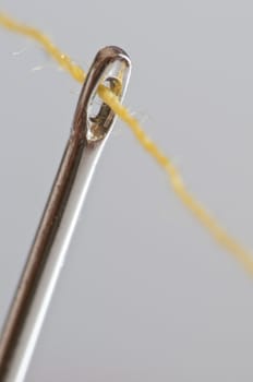 yellow cotton thread through a needle eye