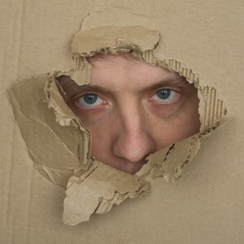 Male face look up from hole in sheet carton