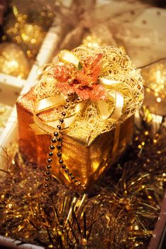 Golden gift boxe with leaf of Mistletoe. Are tied up by tapes with bows
