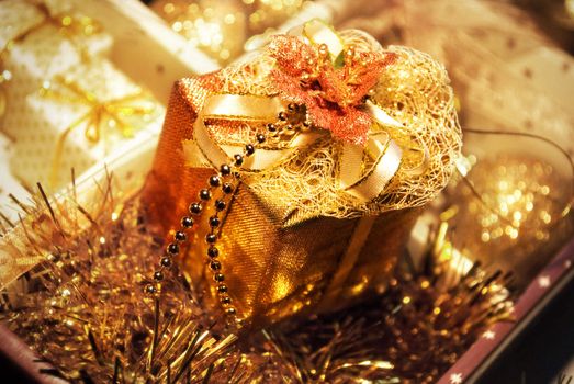 Golden gift boxes with leaf of Mistletoe on glare background. Are tied up by tapes with bows